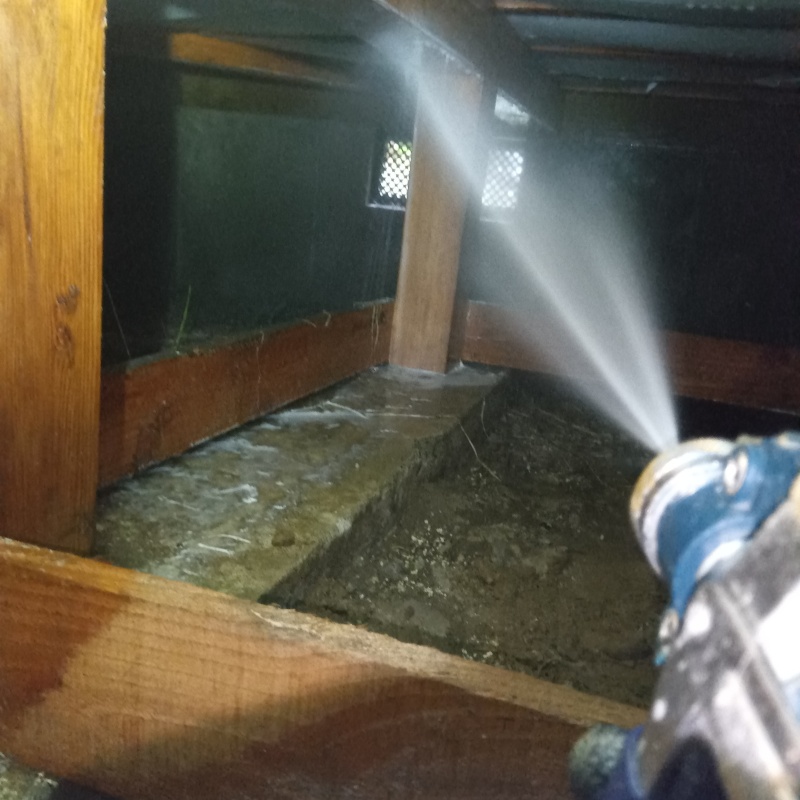 床下断熱材に防蟻剤を吹きつける様子