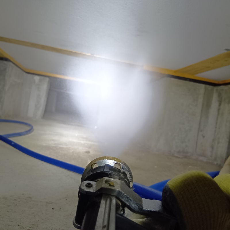 床下断熱材に防蟻剤を吹きつける様子