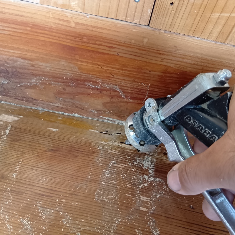 玄関まわりの床材に穴を開けてシロアリ駆除剤を注入