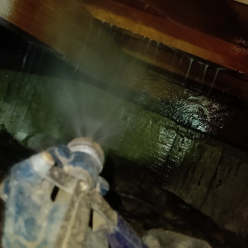 床下木材にシロアリ駆除剤を吹きつける様子