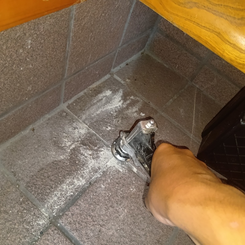 玄関床の目地からシロアリ駆除剤を注入している様子