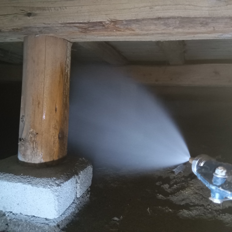 床下木材にシロアリ駆除剤を吹き付ける様子