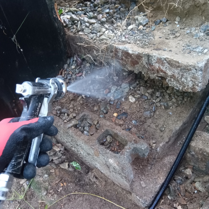 地面にシロアリ駆除剤を吹きつける様子