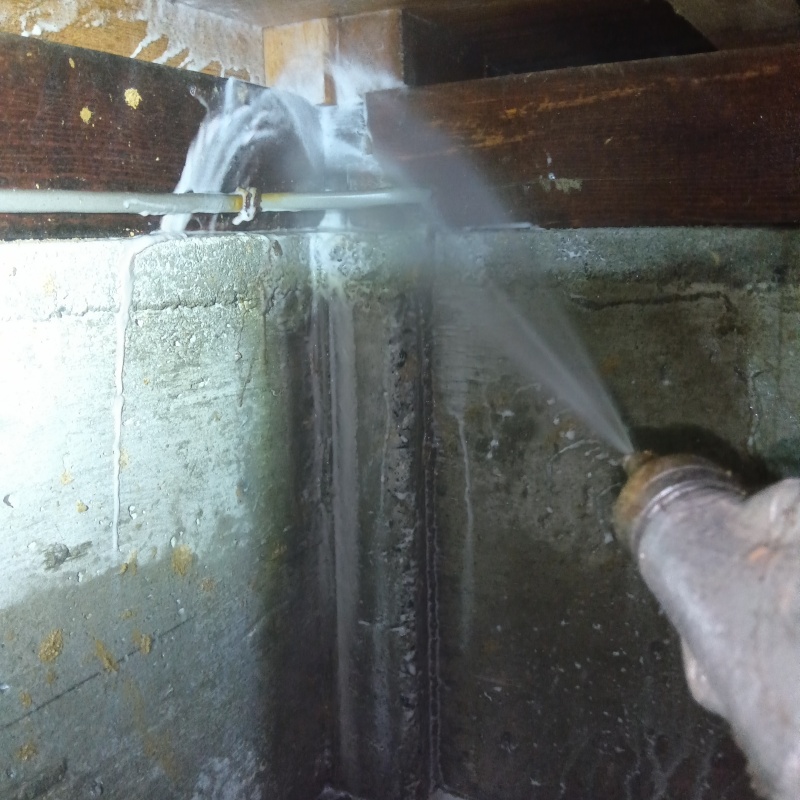 床下木材にシロアリ駆除剤を吹きつける様子