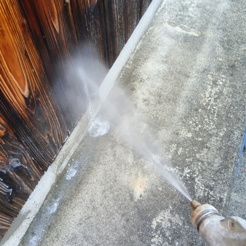 木塀にシロアリ駆除剤を吹きつける様子