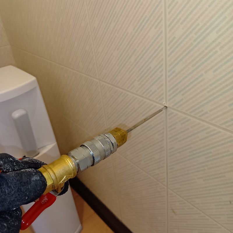 トイレの壁の目地からシロアリ駆除剤を注入