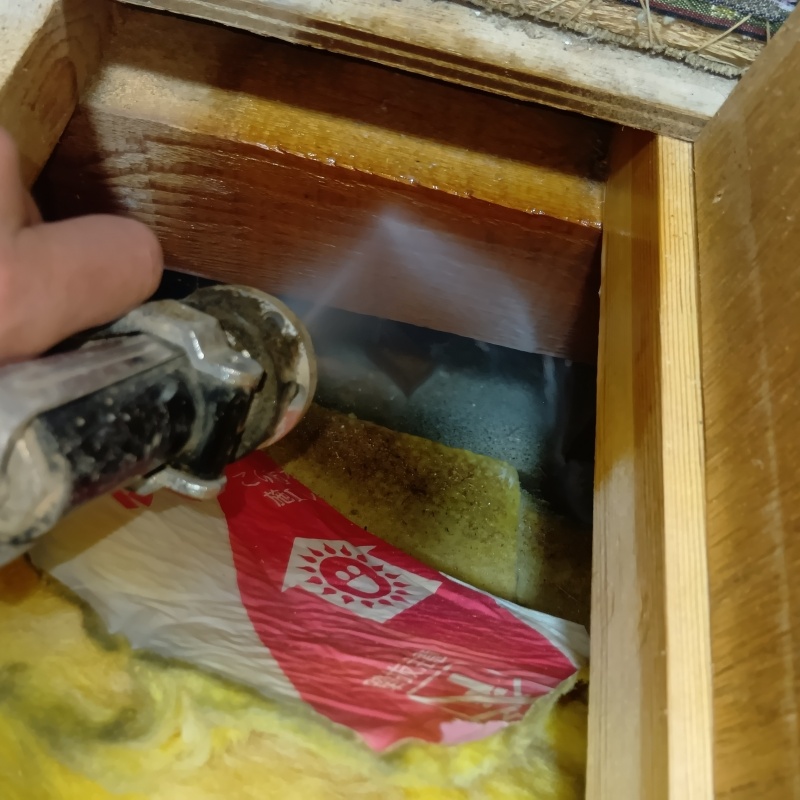 畳近くの木材にシロアリ駆除剤を吹きつけている様子