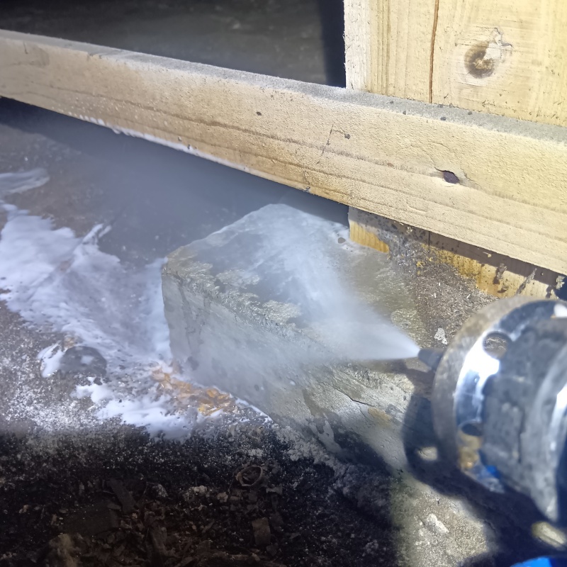 束石まわりにシロアリ駆除剤を吹き付けている様子