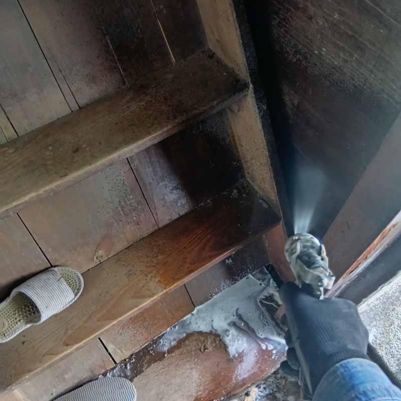 階段まわりの木材にシロアリ駆除剤を吹き付けている様子