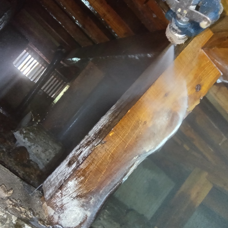 シロアリの被害が著しい木材にシロアリ駆除剤を散布する様子