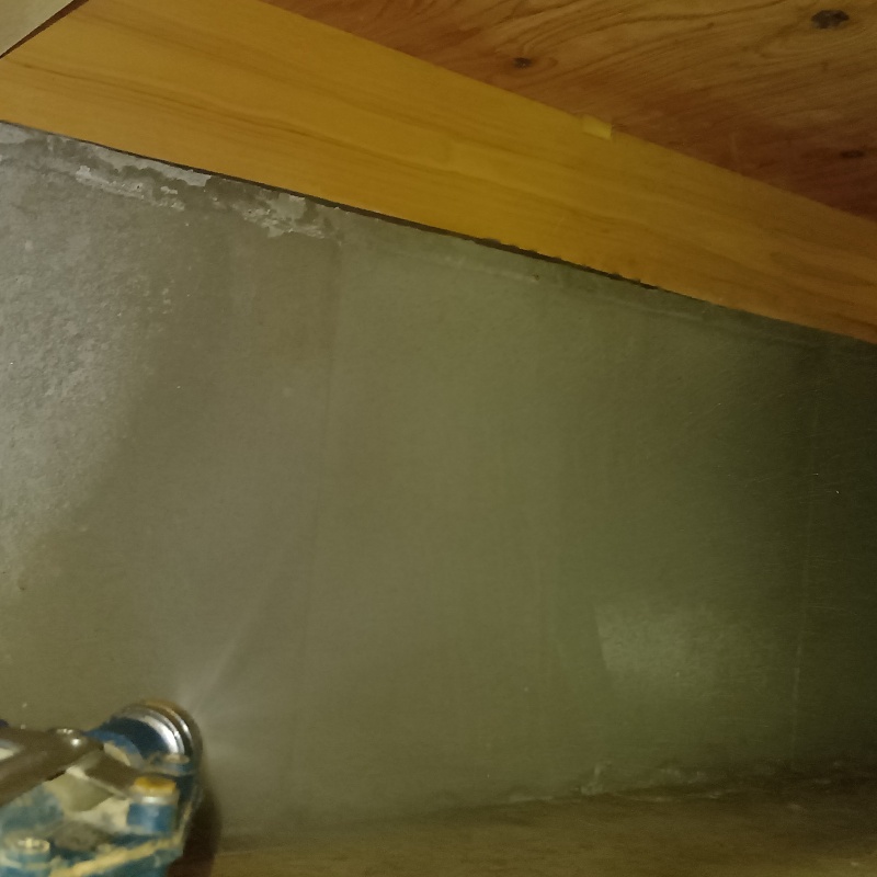 床下の基礎部分に防蟻剤を吹きつけている様子