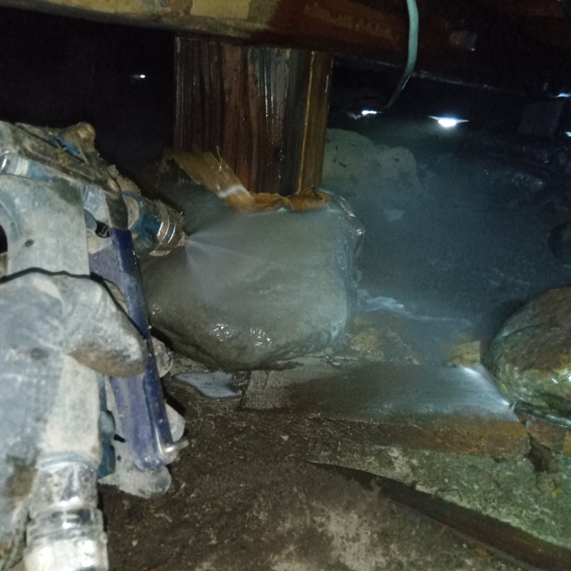 束石まわりにシロアリ駆除剤を吹きつけている様子