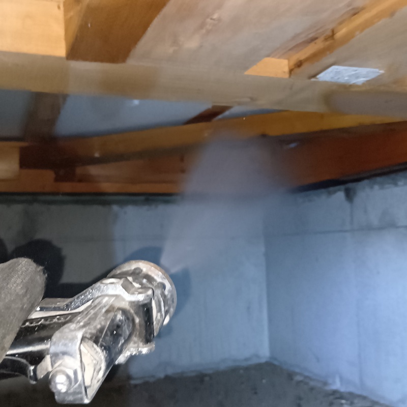 床下木材の隅まで防蟻剤を吹きつけている様子