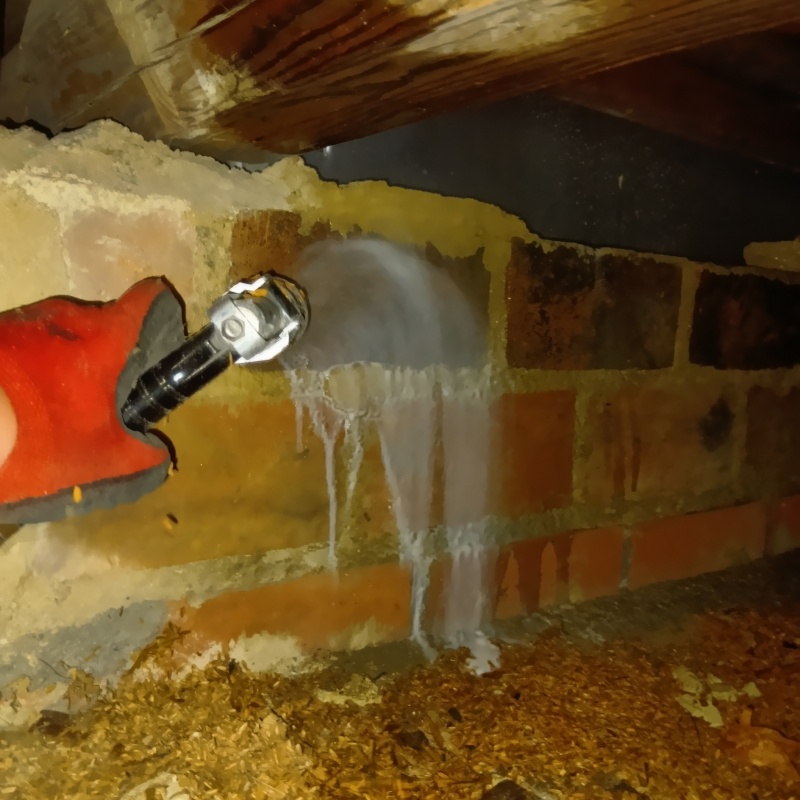 床下の基礎にシロアリ駆除剤を吹き付けている様子