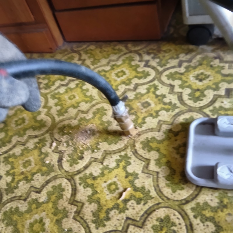 室内床に穴を開けてシロアリ駆除剤を注入している様子