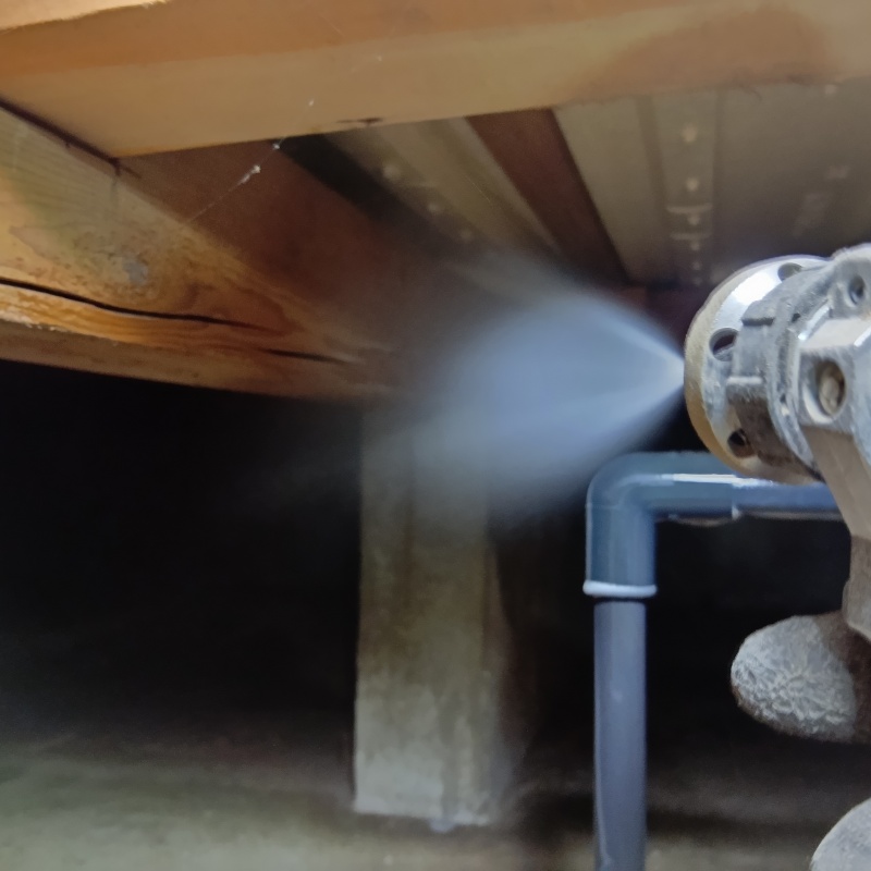 床下の木材にシロアリ駆除剤を吹き付けている様子