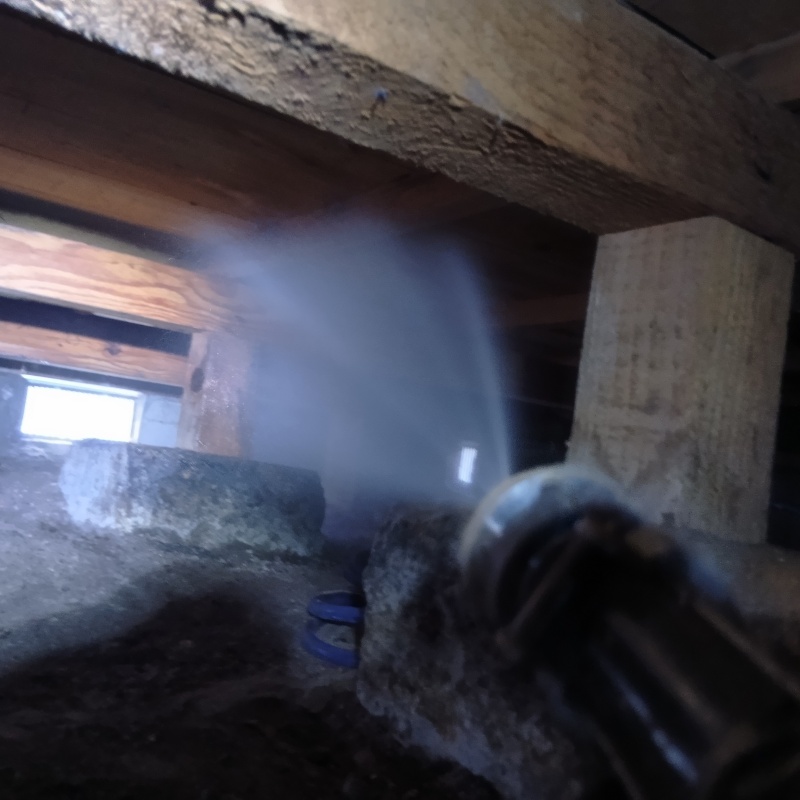 床下の木材に防蟻剤を吹き付けている様子