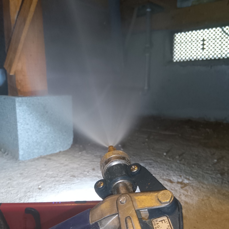 束石に防蟻剤を吹きつけている様子