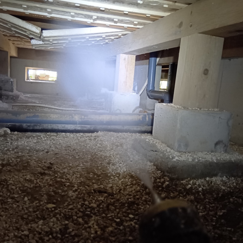 床下の土壌にシロアリ駆除剤を散布する様子