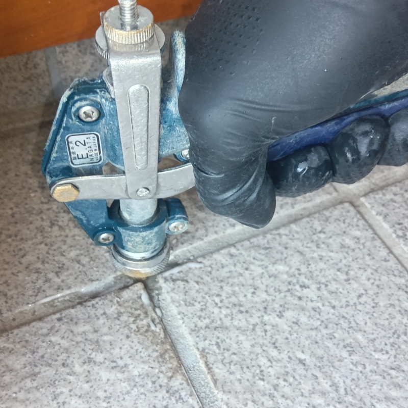 目地からシロアリ駆除剤を注入している様子