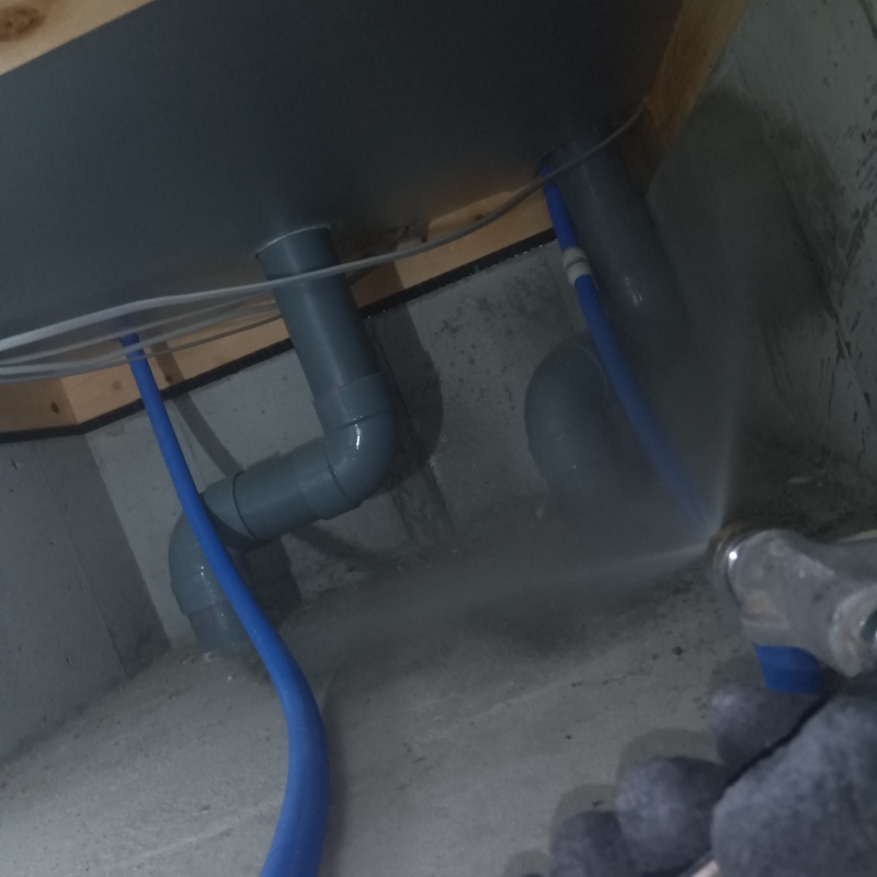 床下の配管まわりに防蟻剤を吹き付けている様子