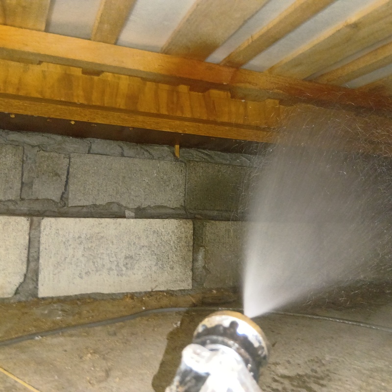 床下の基礎部分にシロアリ駆除剤を散布する様子