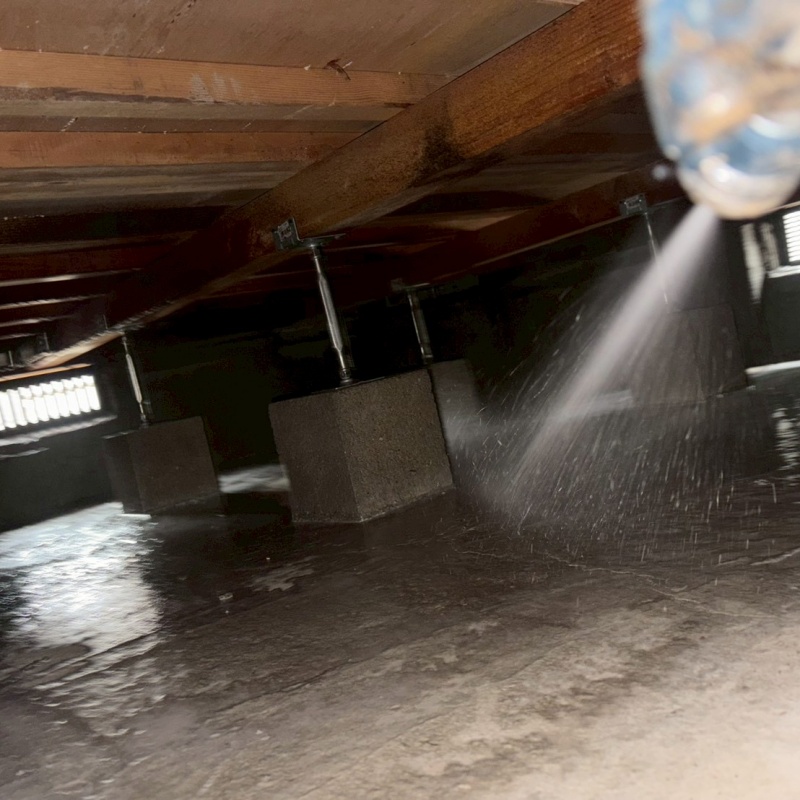 束石まわりに防蟻剤を吹きつけている様子