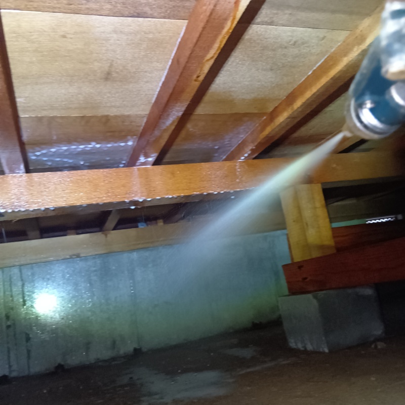 床下の基礎部分にシロアリ駆除剤を散布する様子