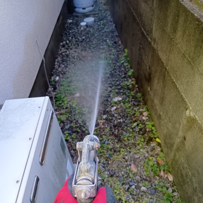 建物外周の土壌にシロアリ駆除剤を吹きつける様子