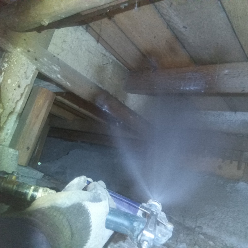 床下木材に防蟻剤を吹きつけている様子
