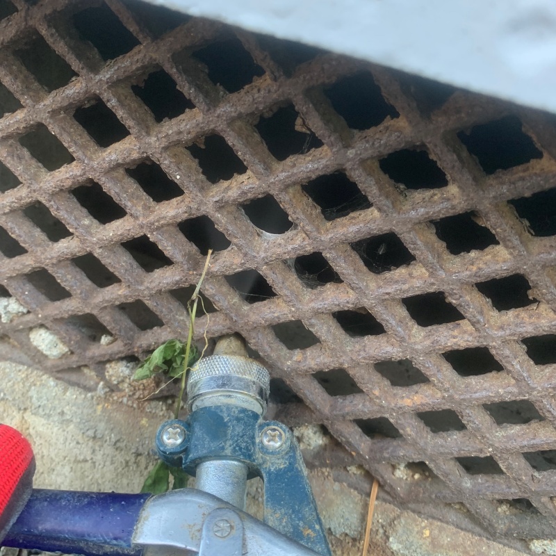 床下換気口からシロアリ駆除剤を散布している様子