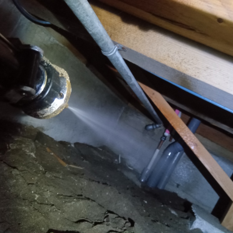 配管まわりの土壌にシロアリ駆除剤を吹きつける様子