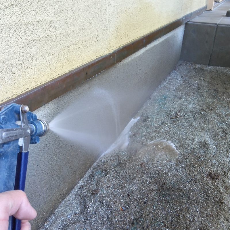 建物外周の土壌にシロアリ駆除剤を吹きつける様子