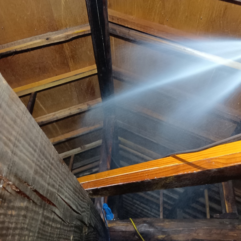 屋根裏の木材にシロアリ駆除剤を散布する様子