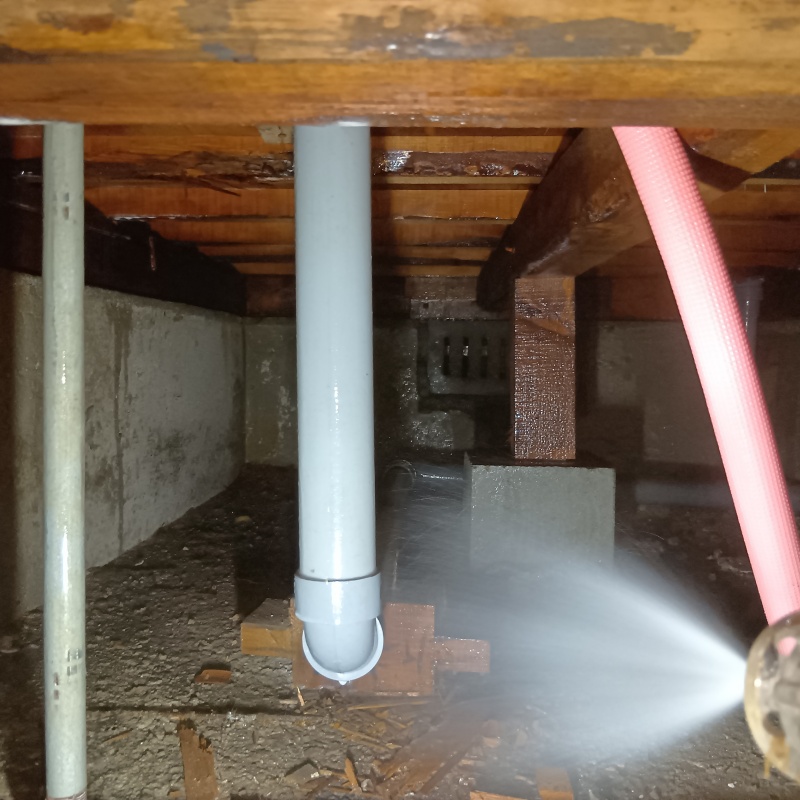 束石まわりにシロアリ駆除剤を吹きつけている様子