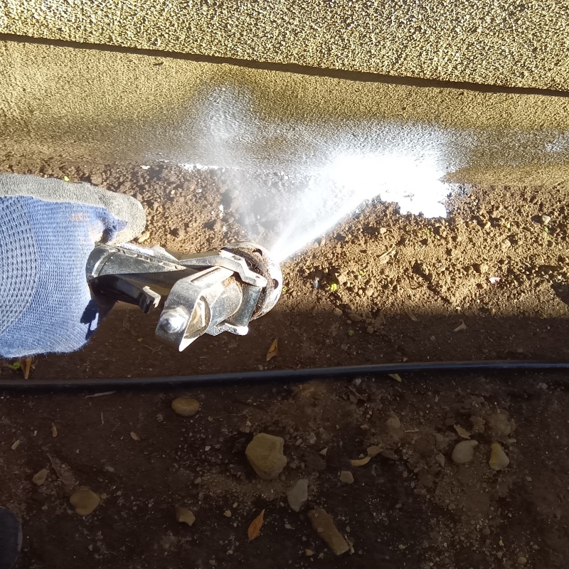 建物外周の土壌にシロアリ駆除剤を吹きつける様子