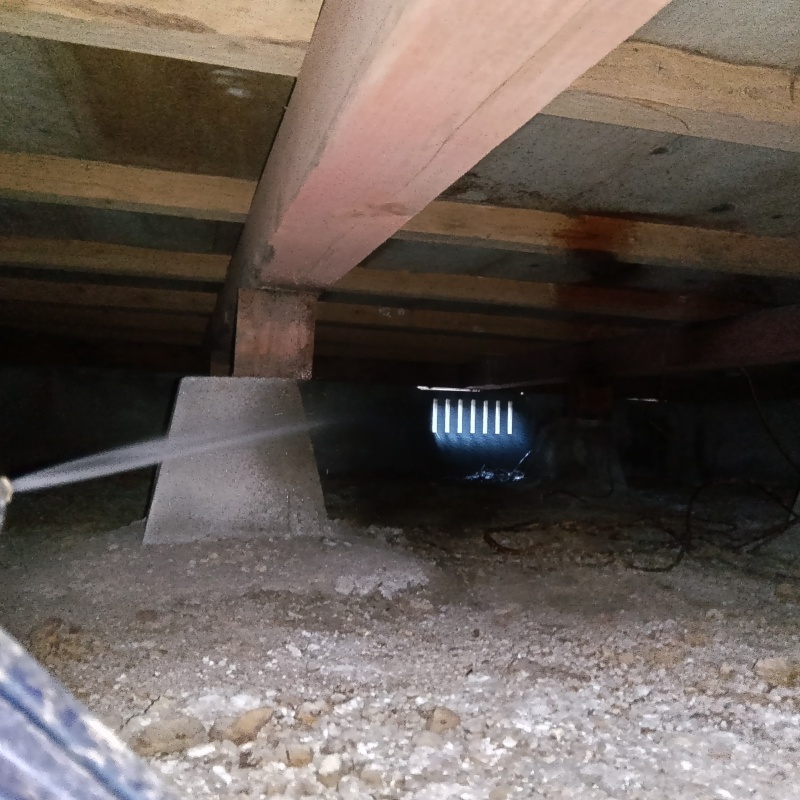 束石まわりに防蟻剤を吹き付けている様子