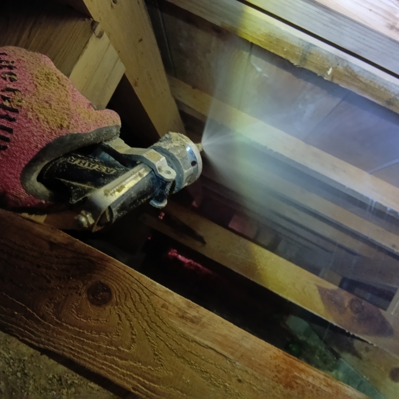 床下木材にシロアリ駆除剤を吹き付ける様子