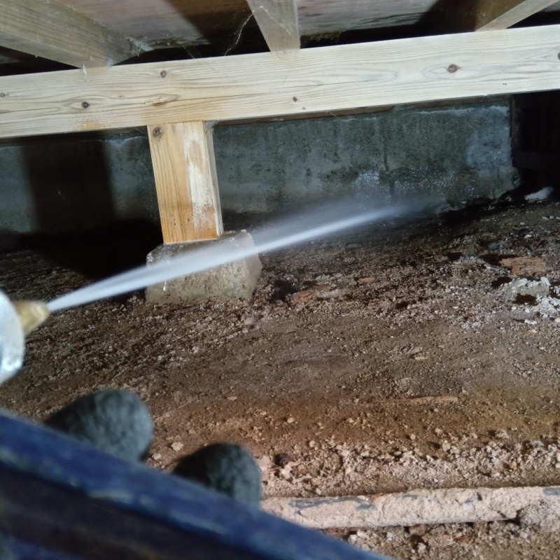 床下の地面にシロアリ駆除剤を散布する様子