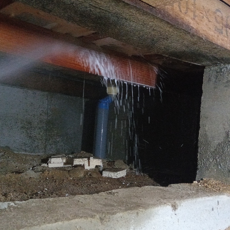 床下木材にシロアリ駆除剤を吹き付ける様子