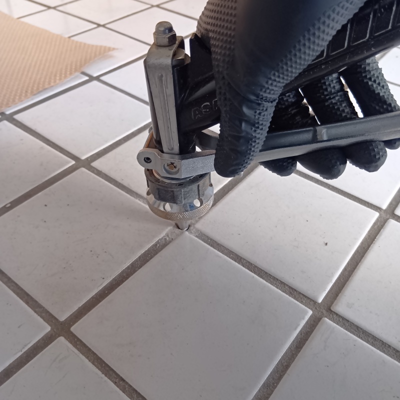 玄関床の目地からシロアリ駆除剤を注入している様子