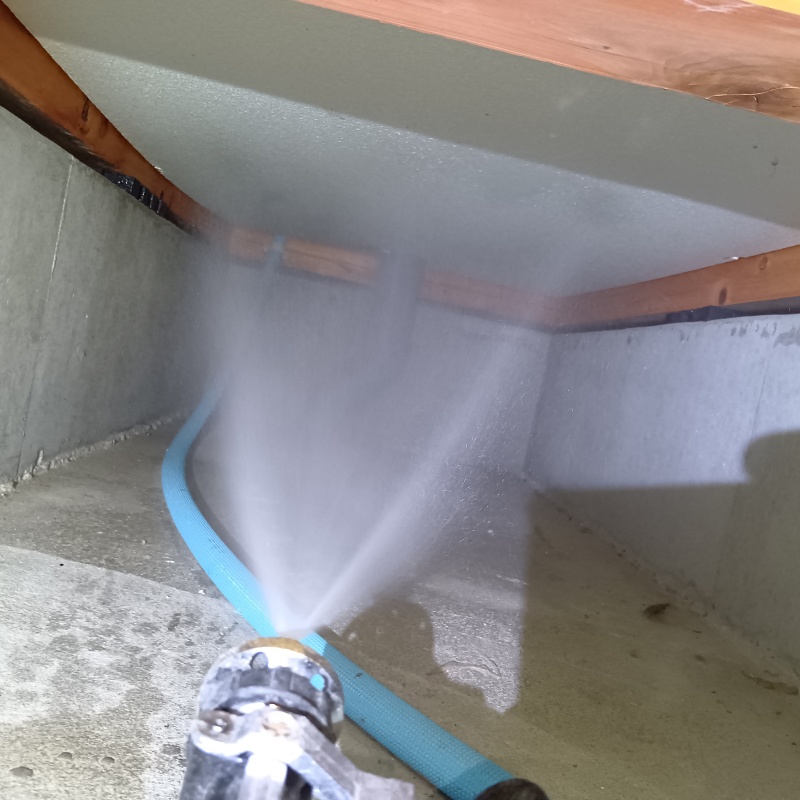 床下断熱材に防蟻剤を吹きつける様子