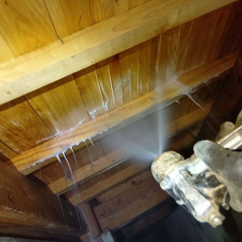 床下木材にシロアリ駆除剤を吹き付ける様子