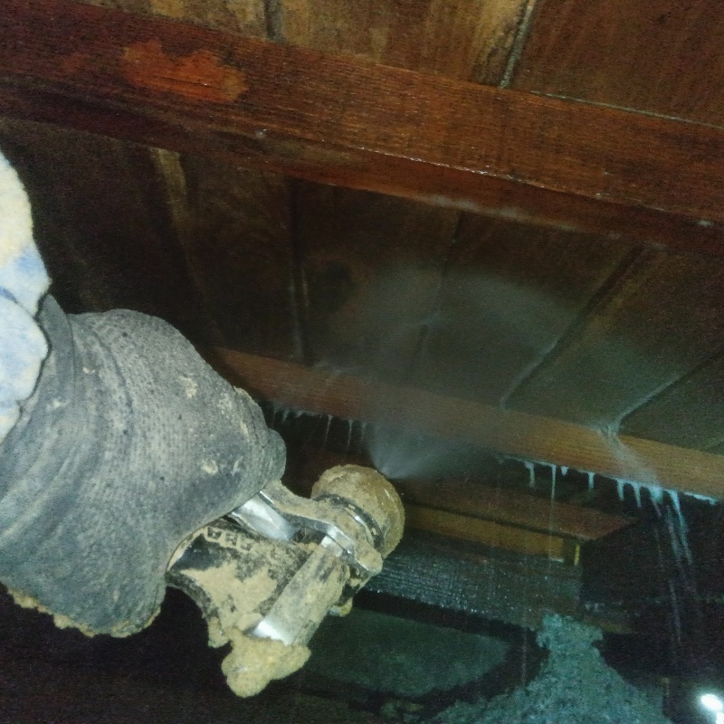 床下木材にシロアリ駆除剤を吹き付ける様子