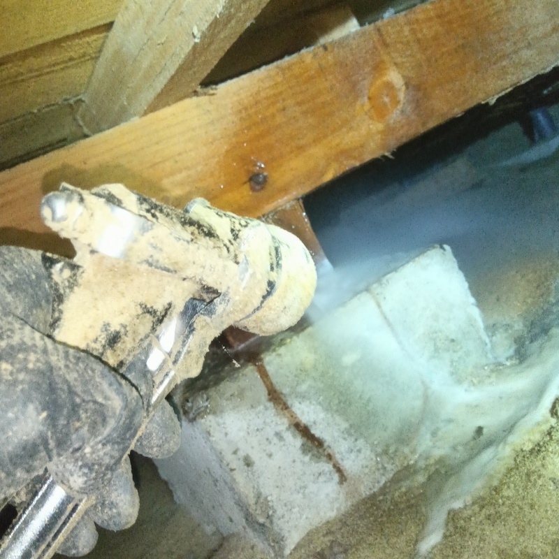 束石まわりにシロアリ駆除剤を吹き付ける様子