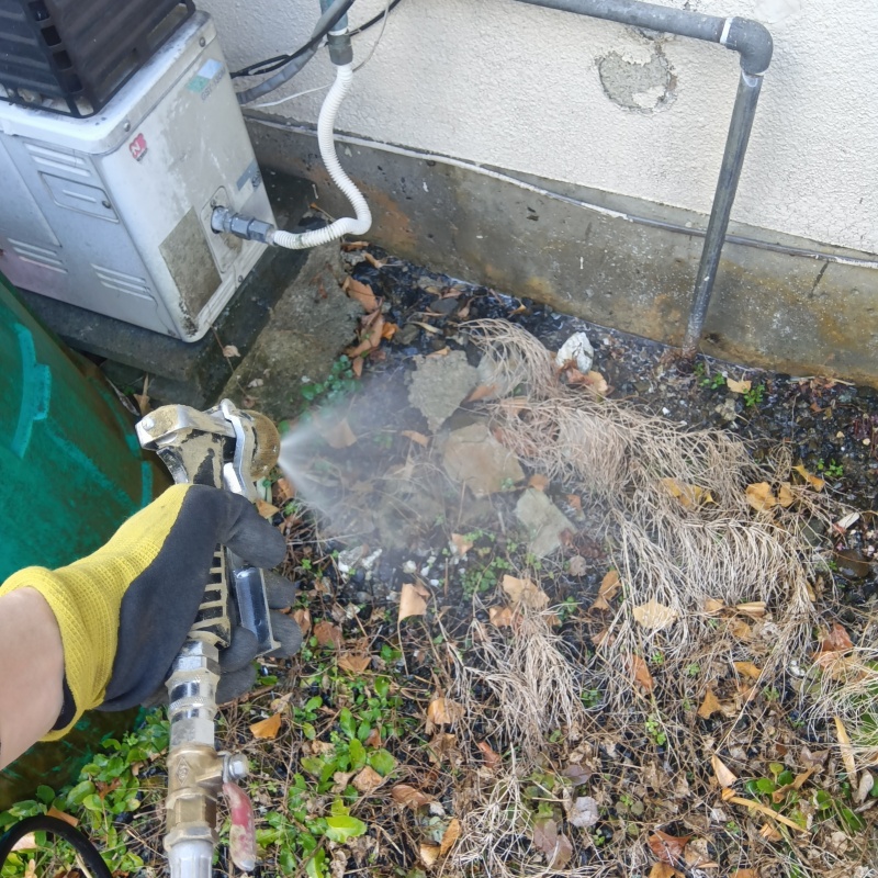 建物外周の土壌にシロアリ駆除剤を吹き付ける様子