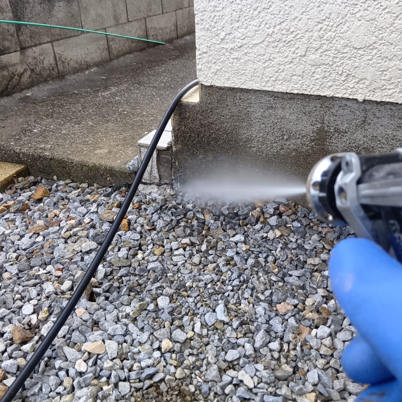 建物外周の土壌にシロアリ駆除剤を散布している様子