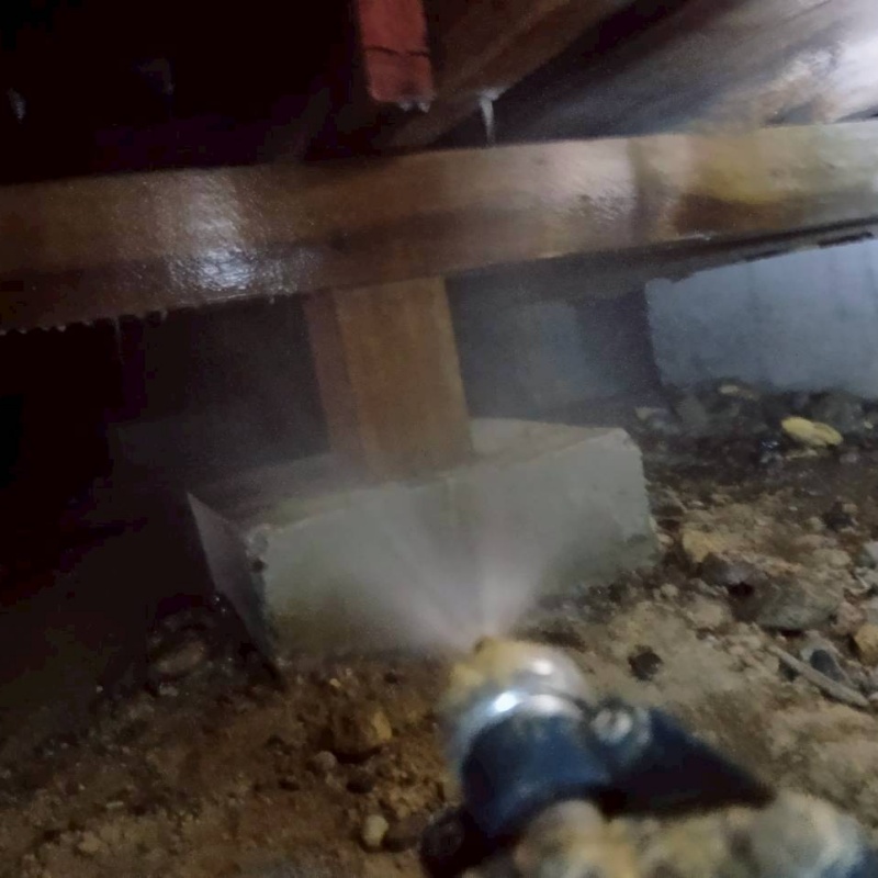 束石まわりにシロアリ駆除剤を吹き付ける様子