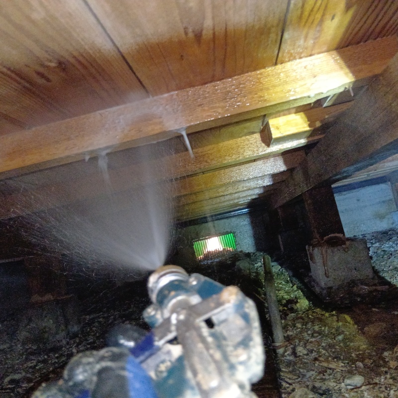 床下木材に防蟻剤を吹き付ける様子