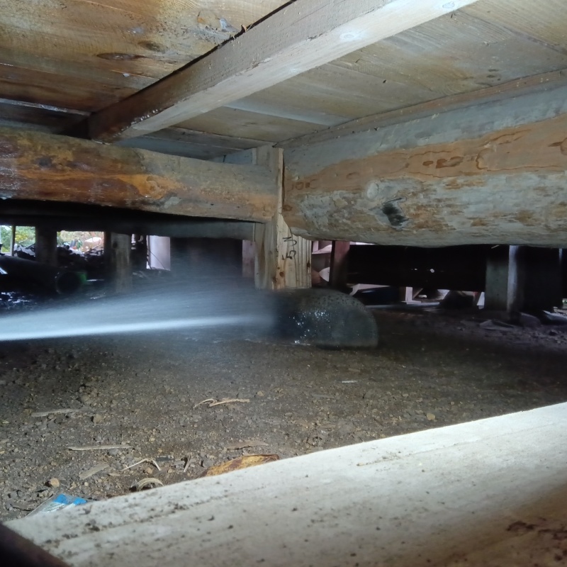 束石まわりにシロアリ駆除剤を吹き付ける様子